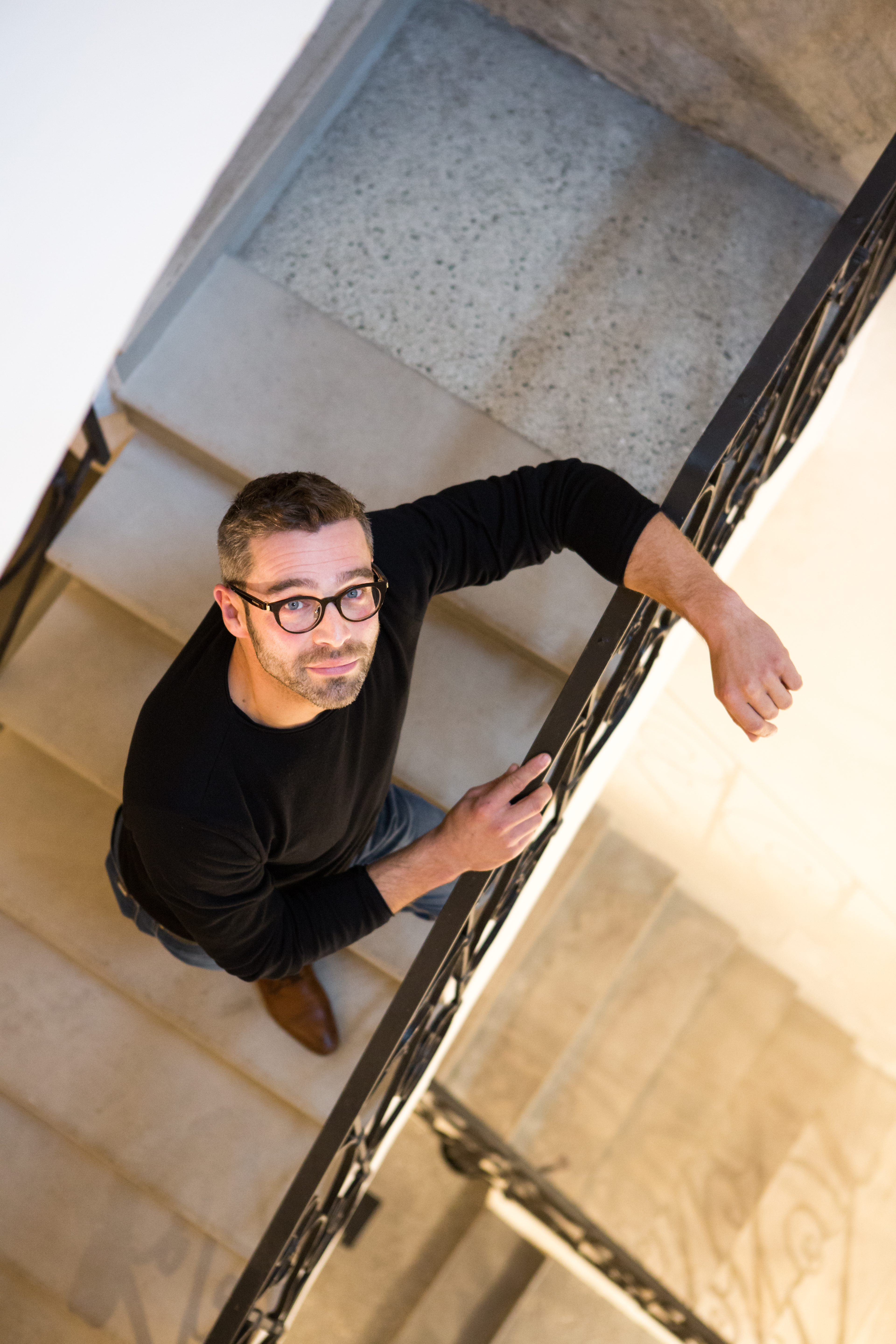 Norbert Öttl steht im Treppengeländer und blickt nach oben in die Kamera 