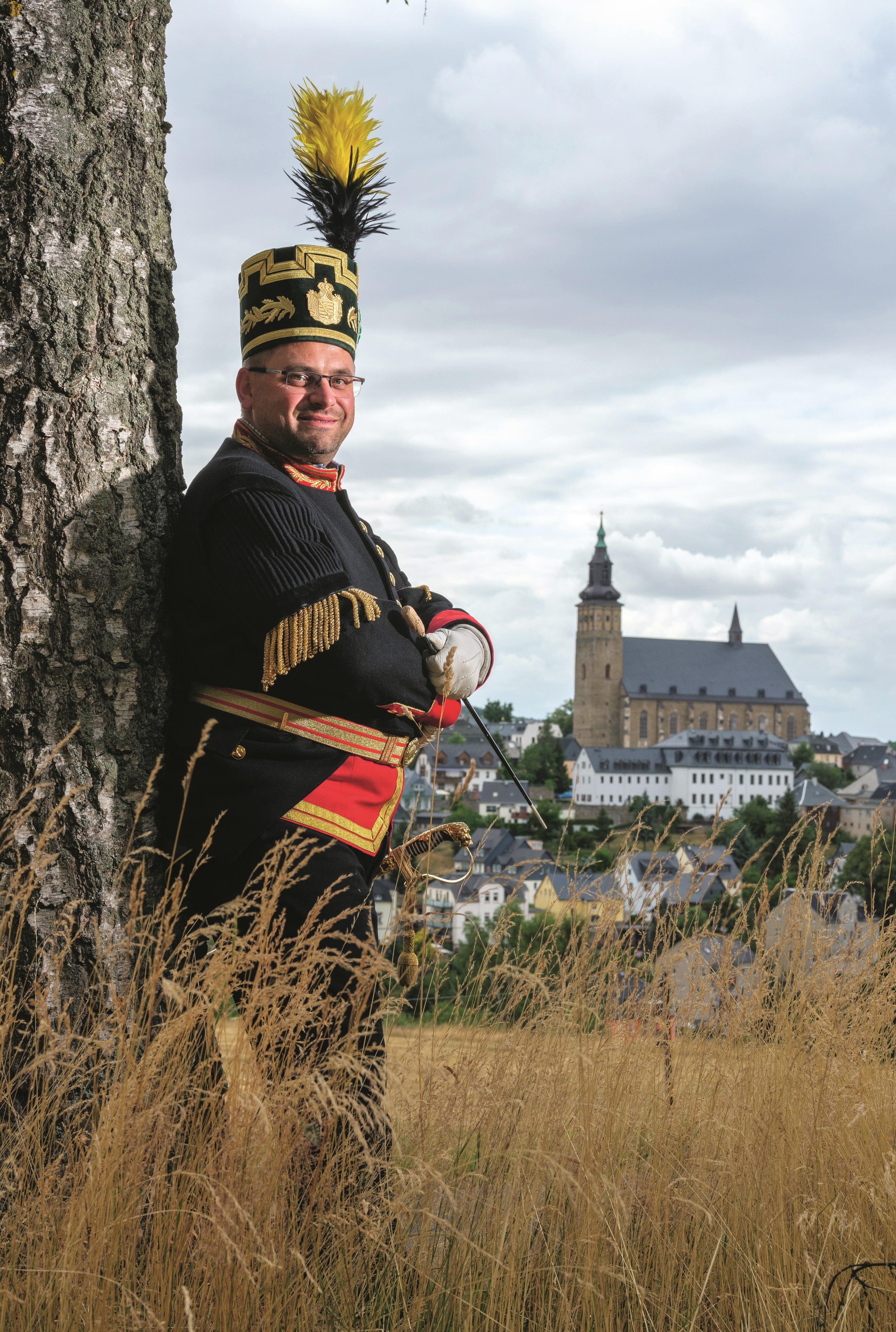 Jens Bretschneider im traditionellen Habit der Bergleute. Im Hintergrund Schneeberg mit seiner St.-Wolfgangs-Kirche