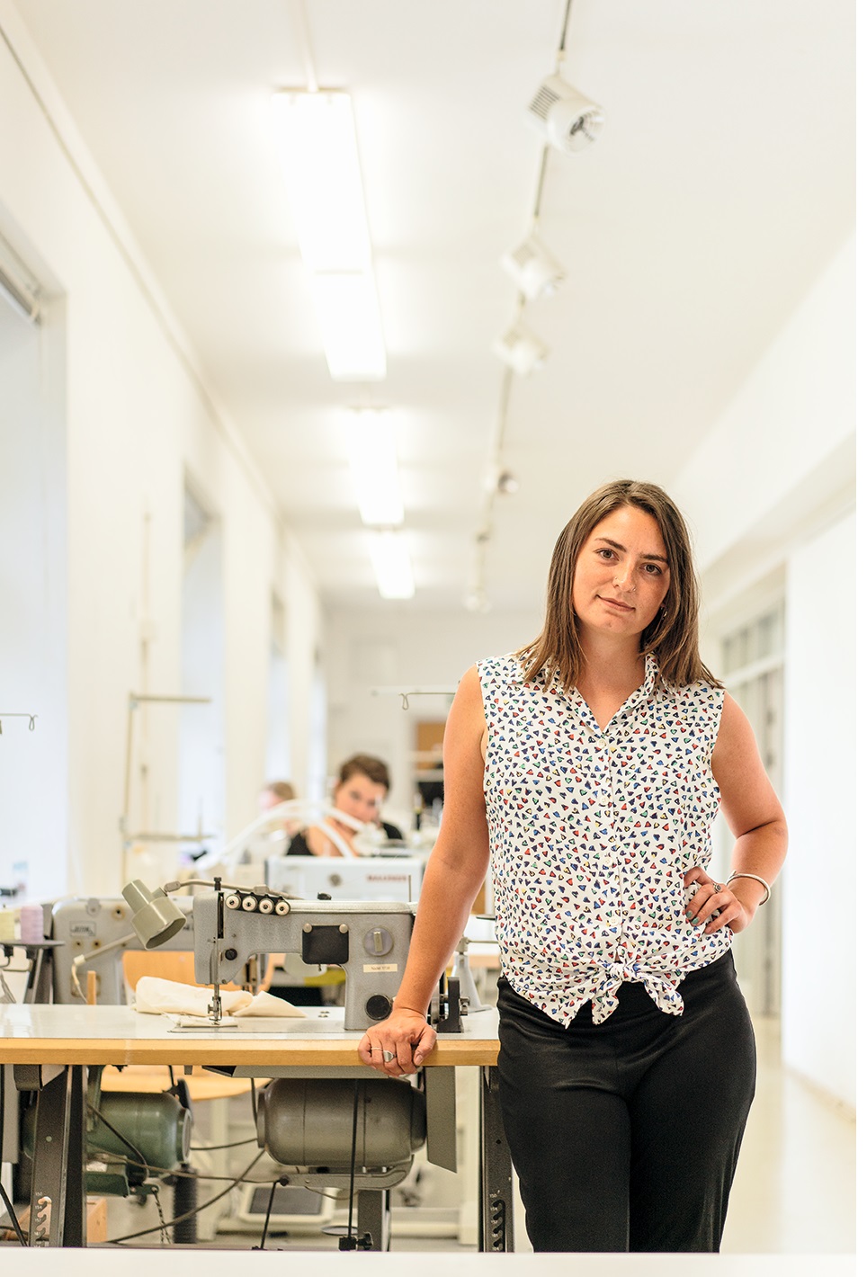 Franziska Heinze in der Werkstatt an den Tisch mit der Nähmaschine gelehnt