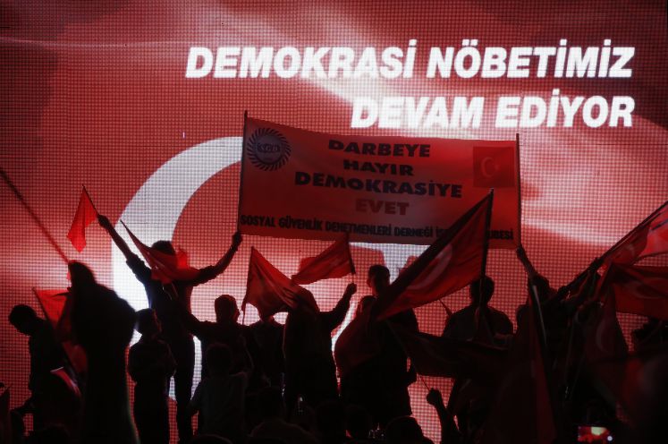 Erdogan-Unterstützer halten bei einer Kundgebung ein Transparent mit der Aufschrift „Nein zum Coup, Ja zur Demokratie“