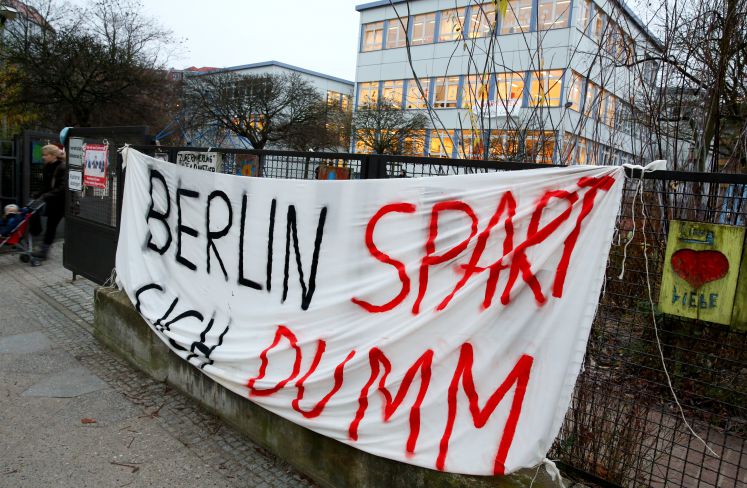 Ein Transparent mit der Aufschrift "Berlin spart sich dumm" hängt vor einem Schulgebäude in Berlin-Steglitz