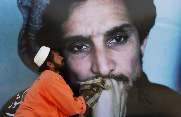 Ein Arbeiter reinigt ein übergroßes Bild des afghanischen Rebellenführers Ahmad Shah Massoud