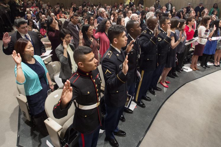 Staatsbürgerschaftskandidaten leisten stehend und mit gehobener Hand den Einbürgerungsschwur. 