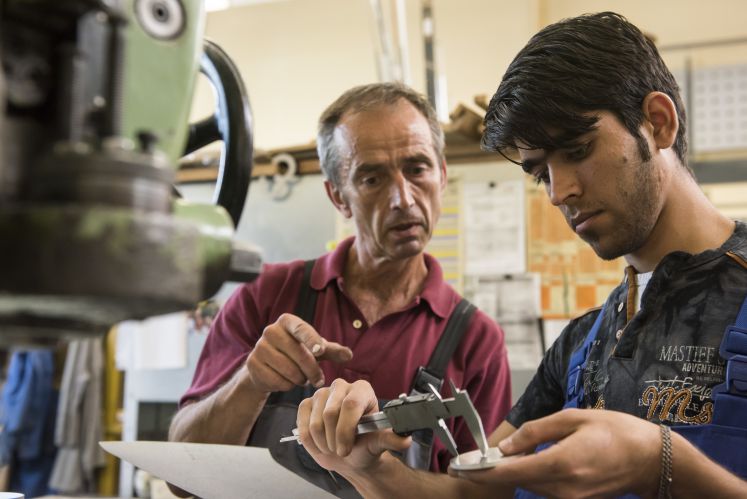 Ein Ausbilder der Jenaer Feinblech GmbH unterhält sich mit einem Flüchtling aus Afghanistan.