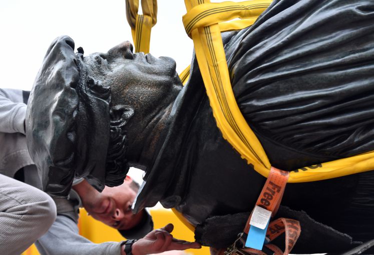 Die Luther-Statue auf dem Marktplatz in Eisleben wird von einem Mitarbeiter der Denkmalpflege für eine Kranfahrt mit Seilen umspannt. 