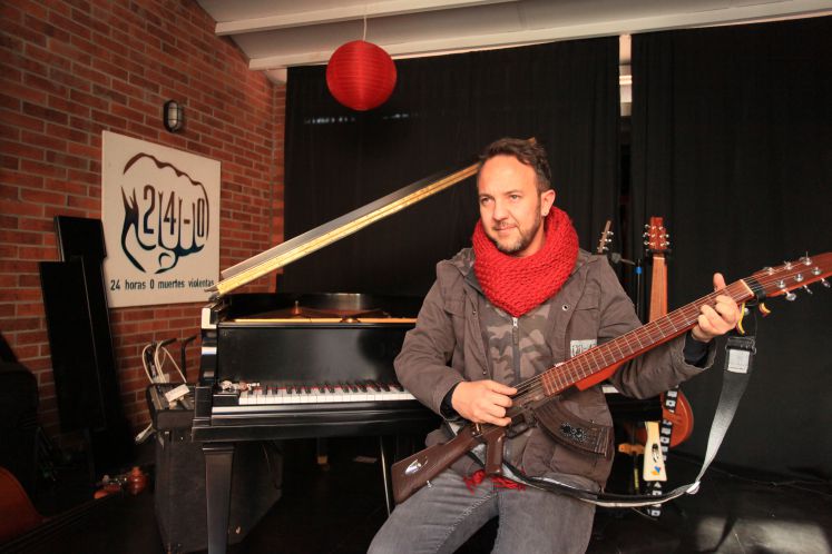 Der Musiker Cesar Lopez spielt auf einer wie ein Gewehr geformten Gitarre 