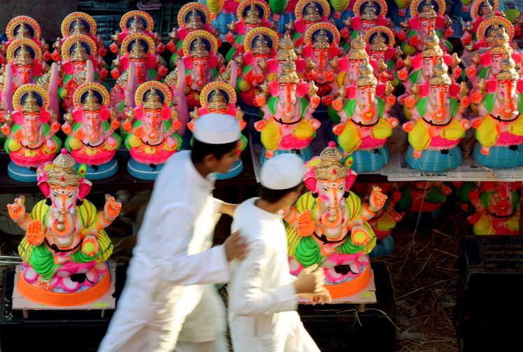 Indische Muslime laufen an hinduistischen Statuen vorbei.
