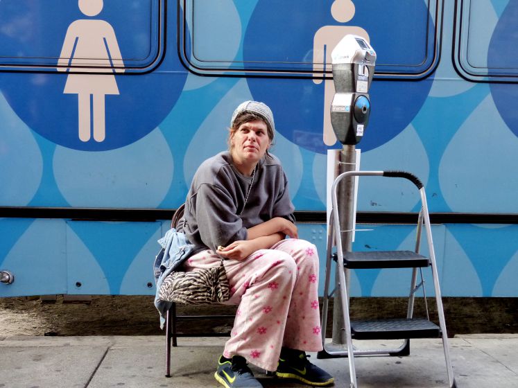 Eine obdachlose Frau wartet von einem Bus mit öffentlichen Duschen