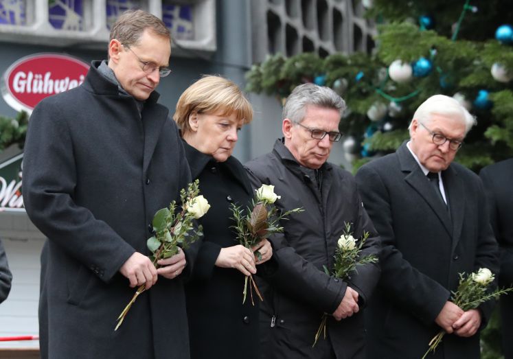 Bundeskanzlerin Angela Merkel (CDU) gedenkt am 20.12.2016 am Ort des Anschlages in Berlin der Opfer zusammen mit Bundesinnenminister Thomas de Maizière (CDU) Außenminister Frank-Walter Steinmeier (SPD (rechts)) und mit dem Regierenden Bürgermeister von Berlin, Michael Müller (SPD, links).