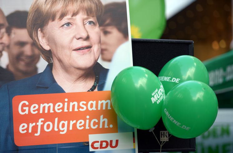 Luftballons der Grünen hängen neben einem Wahlplakat von Bundeskanzlerin Merkel.