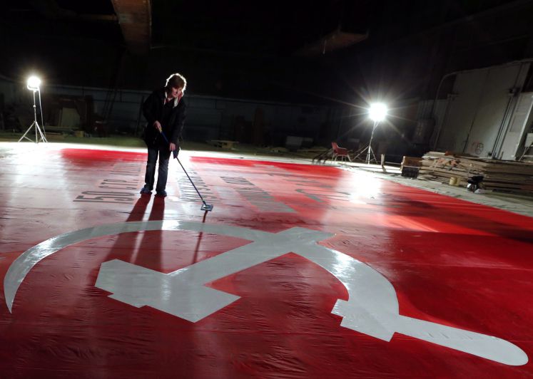 Eine Frau putzt eine Fläche mit den Symbolen der Sowjetunion