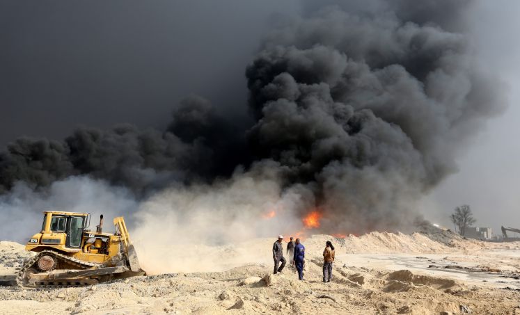 Irakische Ölarbeiter versuchen ein Feuer in einer Ölraffinereie einzudämmen, nachdem sie vom IS befreit wurde