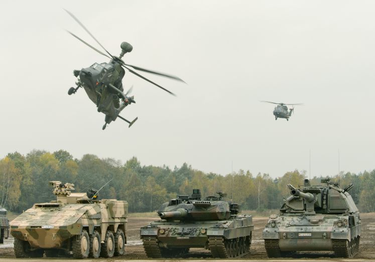 Ein Kampfhubschrauber Tiger (l-r) und ein Mehrzweckhubschrauber NH90 fliegen am 14.10.2016 auf dem Truppenübungsplatz Munster (Niedersachsen) im Rahmen der Informationslehrübung "Landoperationen 2016" über ein gepanzertes Transportkraftfahrzeug (GTK) Boxer (l-r), einen Kampfpanzer Leopard 2 und eine Panzerhaubitze 2000