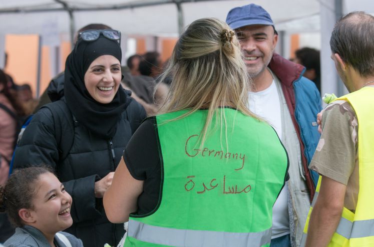 "Germany" steht am 19.09.2015 am Hauptbahnhof in Passau (Bayern) auf der Weste einer Helferin, die mit syrischen Flüchtlingen spricht.