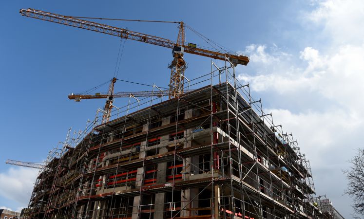 Baustelle eines Wohnungsbaus - dahinter reihen sich die Kräne