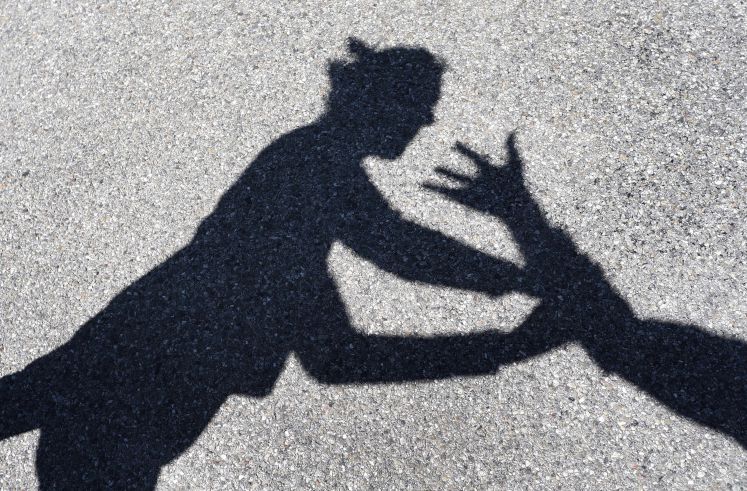 Ein Mann greift nach einer Frau, von beiden sind nur die Schatten zu sehen