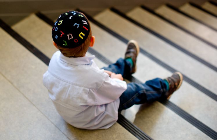 Ein junge mit einer Kippa sitzt auf einer Treppe