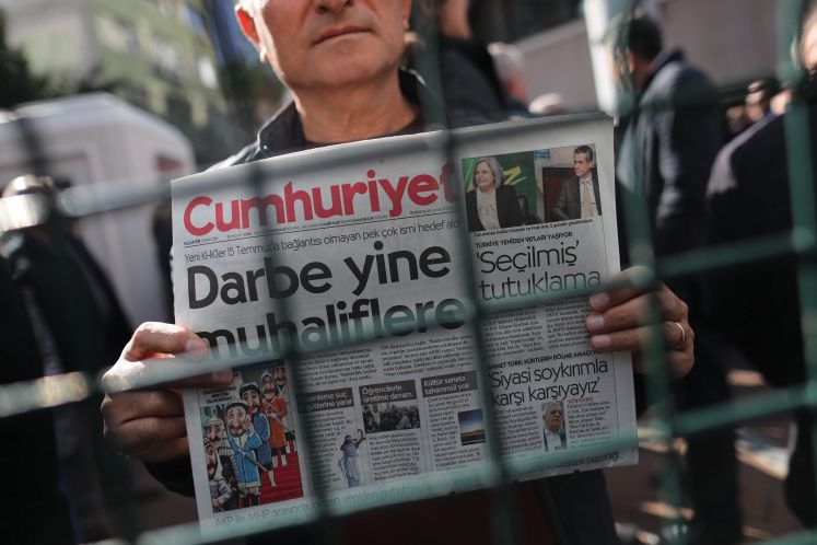 Ein türkischer Mann hält hinter einem Zaun die Ausgabe der Zeitung Cumhurijet hoch am Tag, als ihr Chefredakteur verhaftet wurde