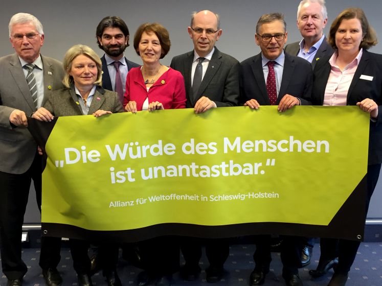 ünter Ernst-Basten (Paritätischer Wohlfahrtsverband), Anke Homann (LandesFrauenRat), Fatih Mutlu (Schura), Irene Johns (Kinderschutzbund), Bischof Gothart Magaard (Nordkirche), Uwe Polkaehn (DGB Nord), Wolfgang Baasch (Arbeiterwohlfahrt) und Beate Bäumer (Kath.Büro Schleswig-Holstein)präsentieren am 19.01.2017 in Kiel (Schleswig-Holstein) ein Transparent mit der Aufschrift "Die Würde des Menschen ist unantastbar". Anlaß dafür ist die Gründung der "Allianz für Weltoffenheit Schleswig-Holstein", der zahlreich
