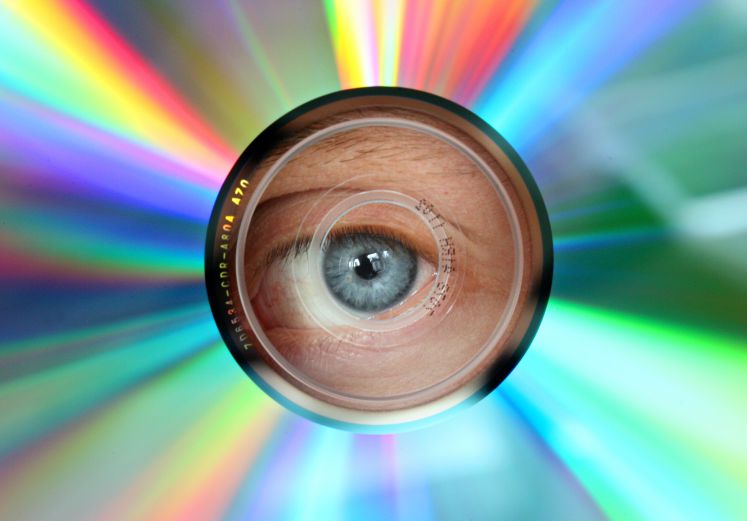Ein Auge schaut durch das Loch einer CD