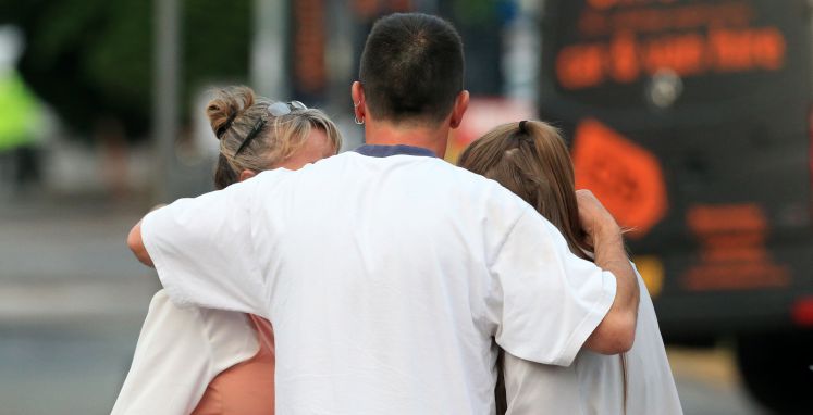 Trauernde Menschen halten sich in Manchester in den Armen