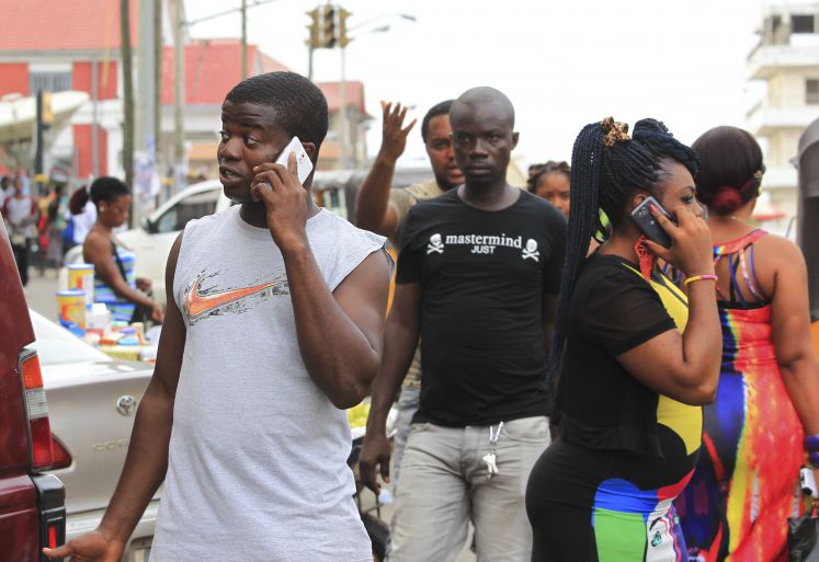 Menschen in Monrovia. Liberia, gehen durch die Straßen mit Mobiltelefonen am Ohr  