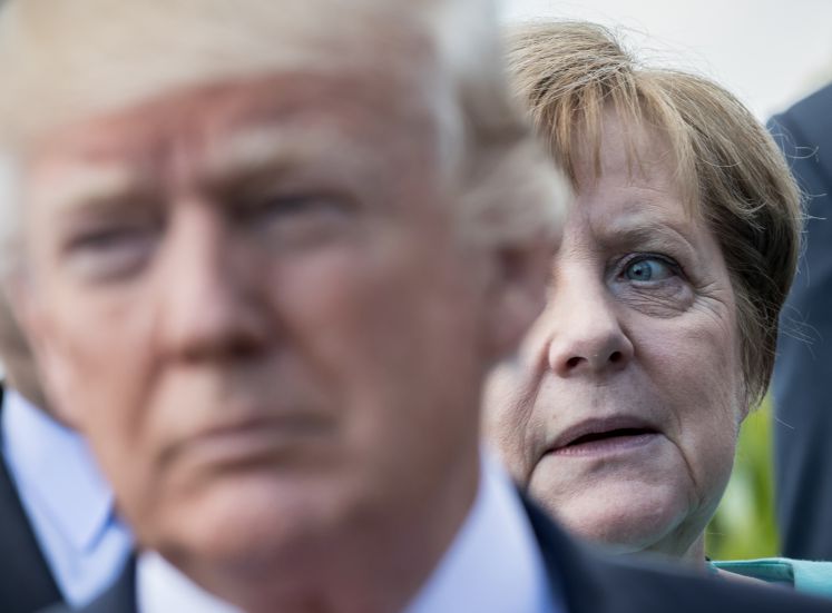 US-Präsident Donald Trump steht vor Bundeskanzlerin Angela Merkel (CDU) am 27.05.2017 beim Familienfoto der G7 Staaten mit den Outreach-Partnern in Taormina auf Sizilien