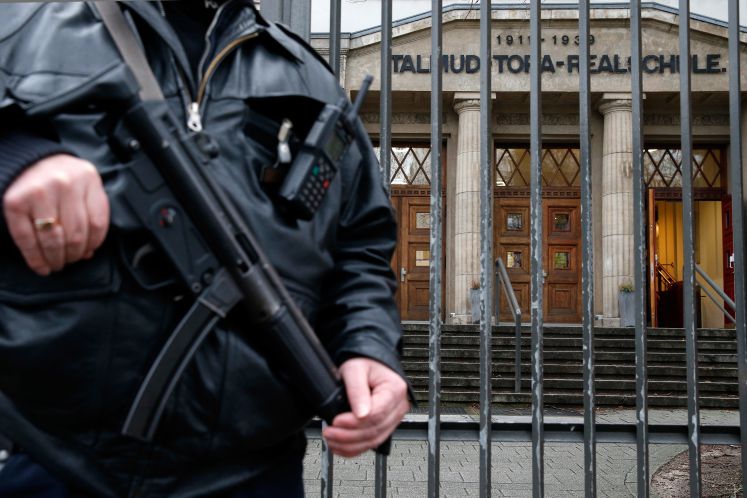 Ein Polizist steht mit einem Maschinengewehr vor dem Gebäude der jüdischen Talmud-Tora-Schule in Hamburg