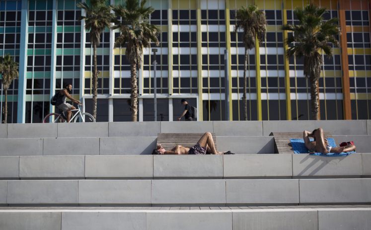 Menschen liegen auf Steintreppenstufen in der Sonne von Tel Aviv