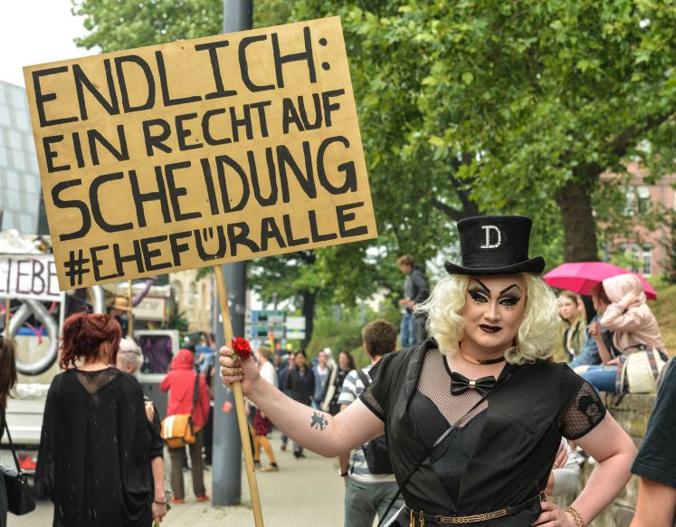 Eine transsexuelle Frau hält ein Schild mit der Aufschrift "Endlich: Ein Recht auf Scheidung #Ehefüralle".