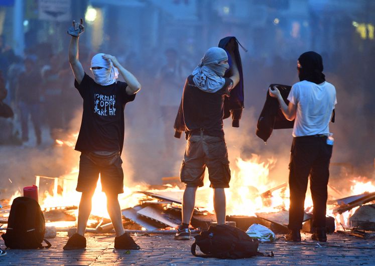 Aktivisten stehen am 07.07.2017 im Schanzenviertel in Hamburg vor einer brennenden Barrikade.