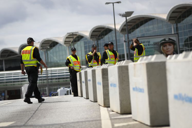 Polizisten stehen vor den Hamburger Messehallen zwischen Betonpollern
