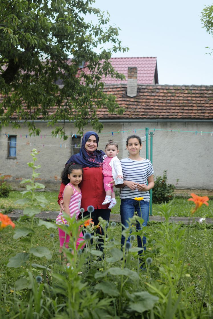 Eine geflüchtete Frau mit ihren drei Töchtern im Garten.