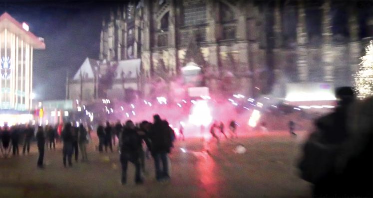 Menschen stehen auf der Domplatte vor dem Dom in Köln in der Silvesternacht.