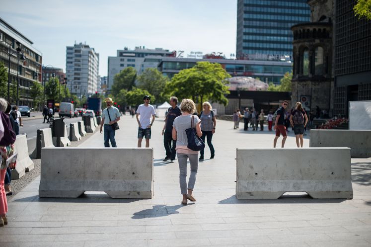 Eine Frau geht in Berlin zwischen Betonbarrieren durch, die rund um den Breitscheidplatz stehen.