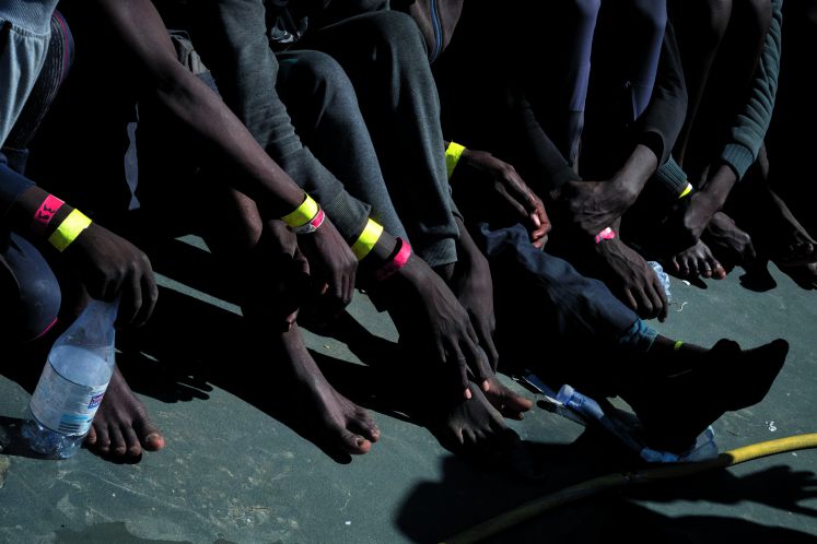 Füße und Hände von Flüchtlingen aus Afrika auf einem Boot der Küstenwache
