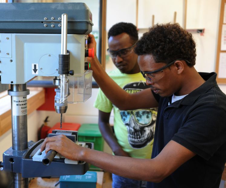 Flüchtlinge bei der Arbeit mit einer Bohrmaschine