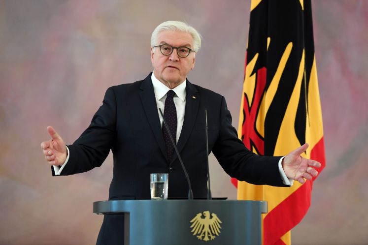 Bundespräsident Frank-Walter Steinmeier steht mit ausgebreiteten Armen am Podium und hält eine Rede