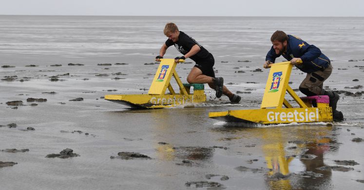Teilnehmer der 34. "Schlickschlitten-Wältmeisterschaften" und Ostfriesischen Wattspiele 2017 schieben im Watt vor dem ostfriesischen Upleward (Niedersachsen) ihren Schlickschlitten. 