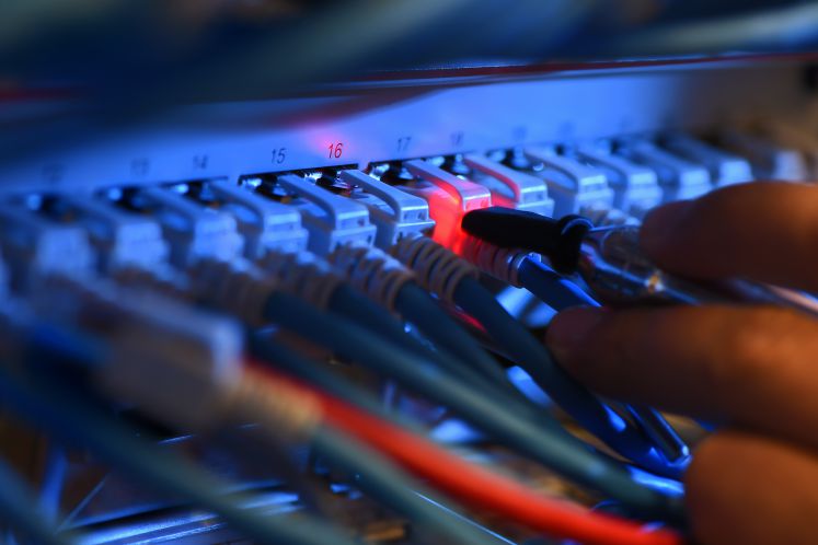 Ein Messe-Mitarbeiter überprüft am 16.10.2014 in der Netzwerkzentrale der Messe Friedrichshafen (Baden-Württemberg) einen rot leuchtenden Netzwerk-Kabelstecker mit einem Detektor.