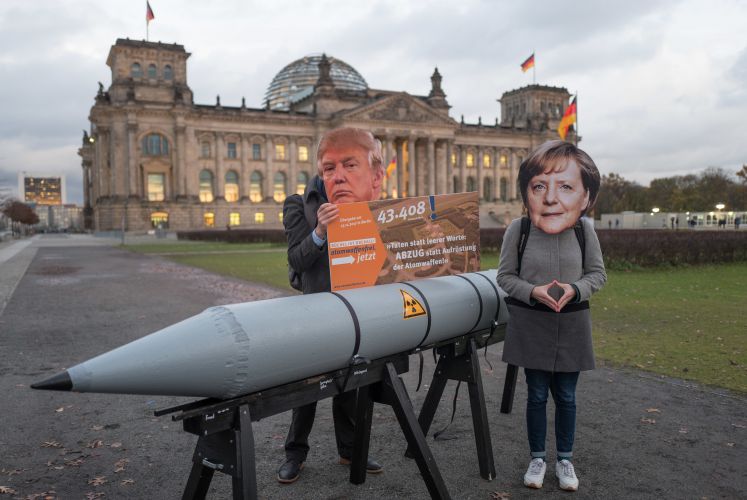 Mit Masken des US-Präsidenten und der Bundeskanzlerin und einer Atombomben-Attrappe stehen Aktivisten am 13.11.2017 vor dem Brandenburger Tor in Berlin und fordert den Stopp der nuklearen Aufrüstung und den Abzug der Atomwaffen aus Büchel (Rheinland-Pfalz). 