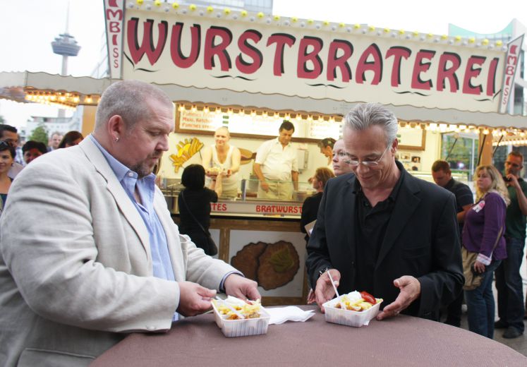 Die Schauspieler Dietmar Bär (l) und Klaus J. Behrendt posieren am Mittwoch (17.08.2011) vor dem Cinedom in Köln vor der "Wurstbraterei".