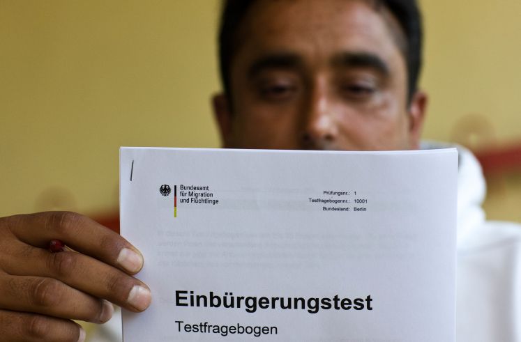 Der Inder Devender Singh schaut sich einen Testfragebogen des Einbürgerungstestes an.