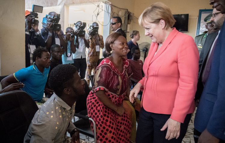 Bundeskanzlerin Angela Merkel (CDU) spricht am 10.10.2016 in Niamey im Niger im Aufnahme- und Durchangszentrum für Migranten der Internationalen Organisation für Migration mit Migranten (IOM) mit Flüchtlingen wie der Liberianerin Binta (M), die im Niger gestrandet sind. 