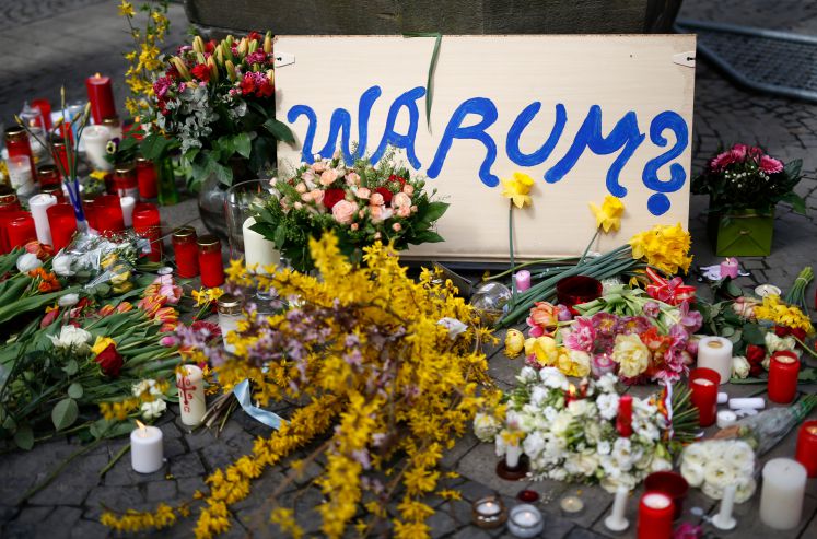 Schild mit der Aufschrift "Warum?", Blumen und Kerzen vor dem Kiepenkerl in Münster