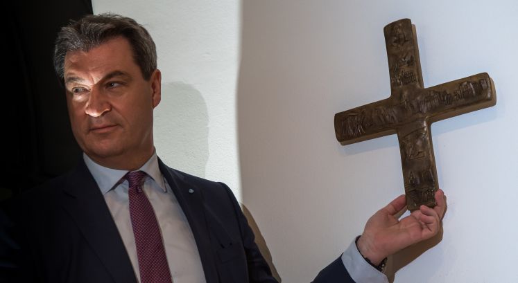 24.04.2018, Bayern, München: Markus Söder, Bayerischer Ministerpräsident (CSU), hängt ein Kreuz im Eingangsbereich der bayerischen Staatskanzlei auf.