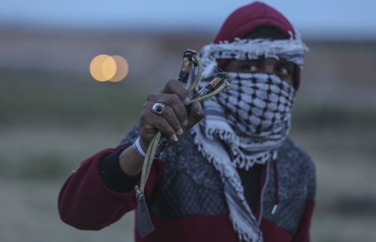 Palästinensische Autonomiegebiete, Gaza: Ein Palästinenser hält während Zusammenstößen zwischen Demonstranten und israelischen Soldaten an der Grenze zu Israel eine Steinschleuder. 