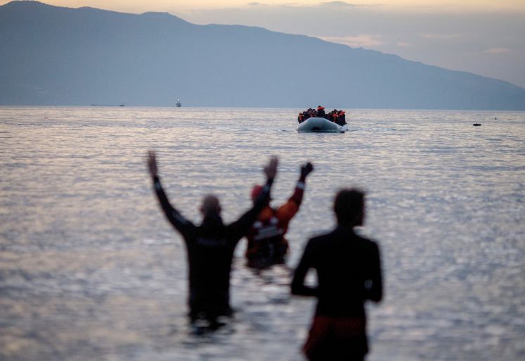 Flüchtlinge kommen am 09.03.2016 in einem Schlauchboot aus der Türkei auf der griechischen Insel Lesbos in der Nähe der Hafenstadt Mitilini (Mytilini) an und werden von Helfern (vorne) erwartet. In der Nacht sind zahlreiche Boote an den Stränden im Süden der Insel angelandet.