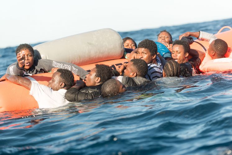 Zahlreiche Flüchtlinge, die auf Booten von Libyen aus nach Italien übersetzen wollten, klammern sich während eines Rettungseinsatzes am 27.01.2018 vor der libyschen Küste an einen Rettungsschlauch der Hilfsinitiative SOS Mediterranee.