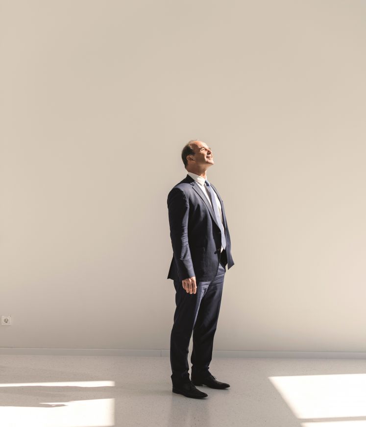 BASF-Chef Martin Brudermüller steht in einem weißen Raum und blickt von oben Richtung Sonnenstrahlen